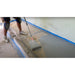 Installer rolling a gray tinted floor coating onto prepped concrete with taped-off edges