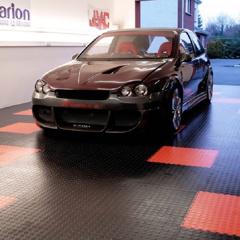 Coin Floor By SupraTile Showing A Car Parked On Black And Red Interlocking PVC Tiles