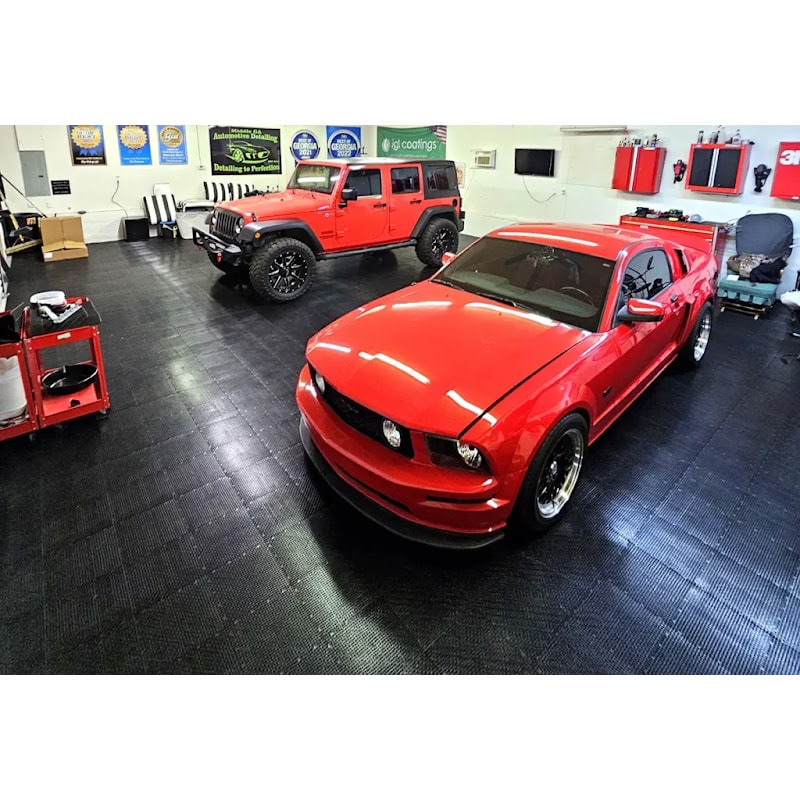Garage interior featuring Garage Flow Race Deck Flooring, showcasing a red Mustang and a Jeep on a sleek black tile surface