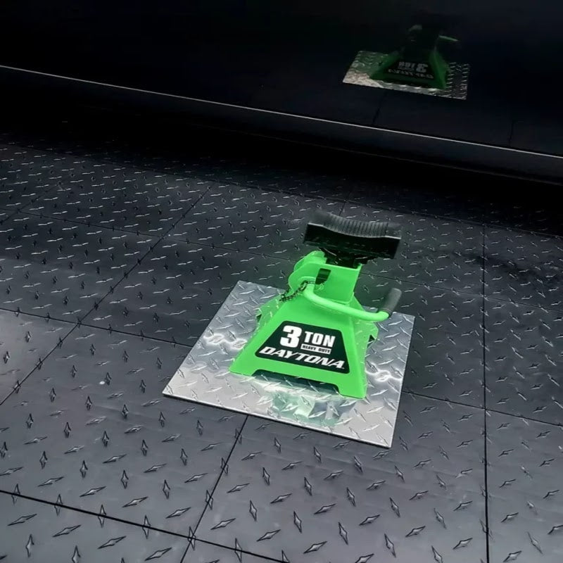 
Garage interior featuring Max Race Deck Floors, highlighting a green jack on a sleek black tile surface for a modern look