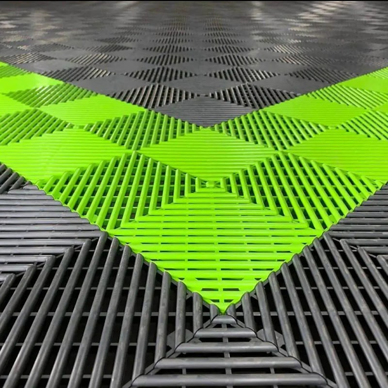 Close-up of RaceDeck Free-Flow XLC flooring, featuring a vibrant green diamond pattern interspersed with black tiles for a modern look