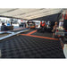 Racing event setup featuring RaceDeck Free-Flow XLC flooring, showcasing a team working in a tent with a car and equipment on a checkered floor