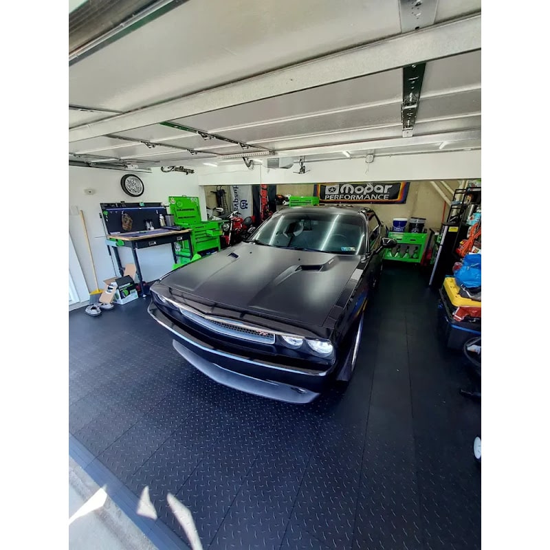 Well-organized garage with RaceDeck Garage Flooring, showcasing a black Dodge Challenger on a stylish black floor with various tools and equipment