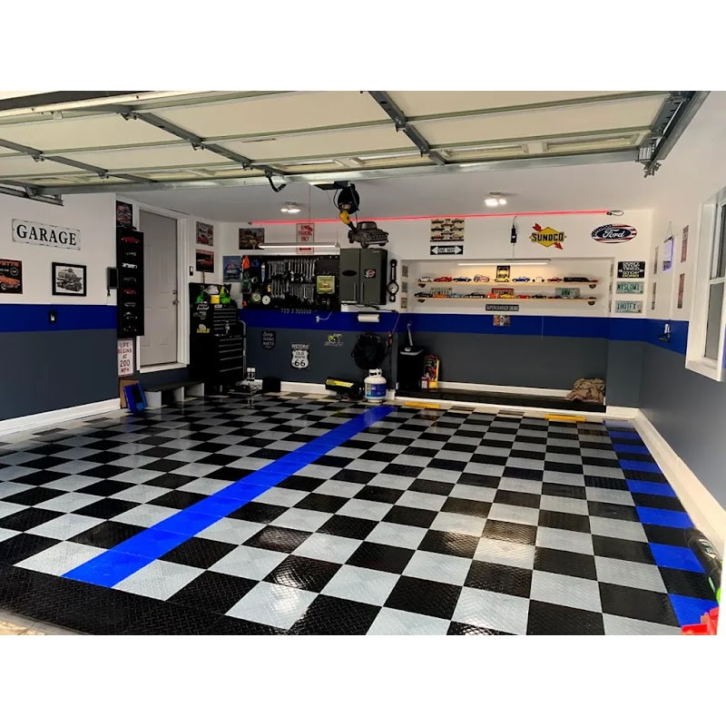 Modern garage interior featuring RaceDeck TuffShield Diamond Flooring Tiles, showcasing a stylish black and blue checkered floor, organized tools