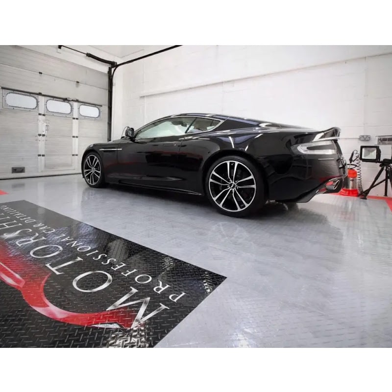 Sleek garage showcasing TuffShield Racedeck Garage Flooring, featuring a black sports car on a reflective surface with a professional logo