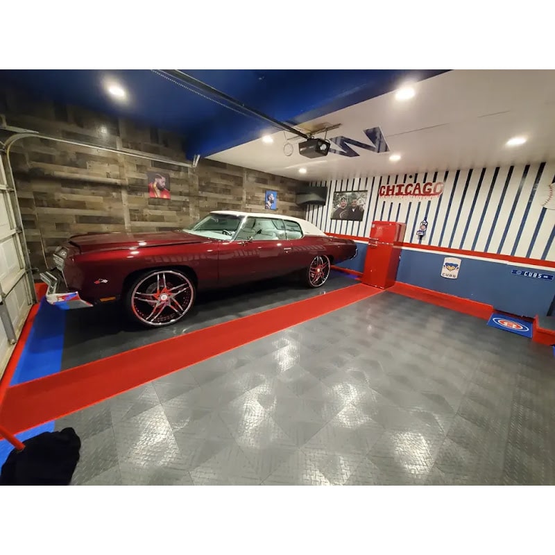 Themed garage using RaceDeck TuffShield tiles, featuring a vintage car on a unique red and black floor with decorative wall accents