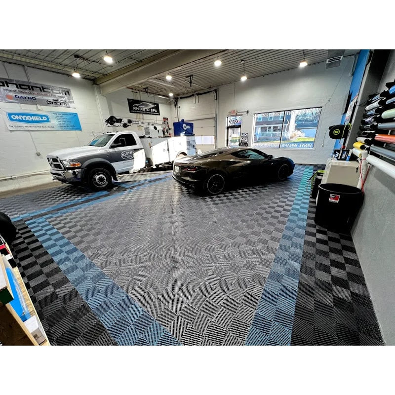 Modern garage with RaceDeck Tiles XLC, featuring a black sports car and a truck on a stylish blue and black checkered floor