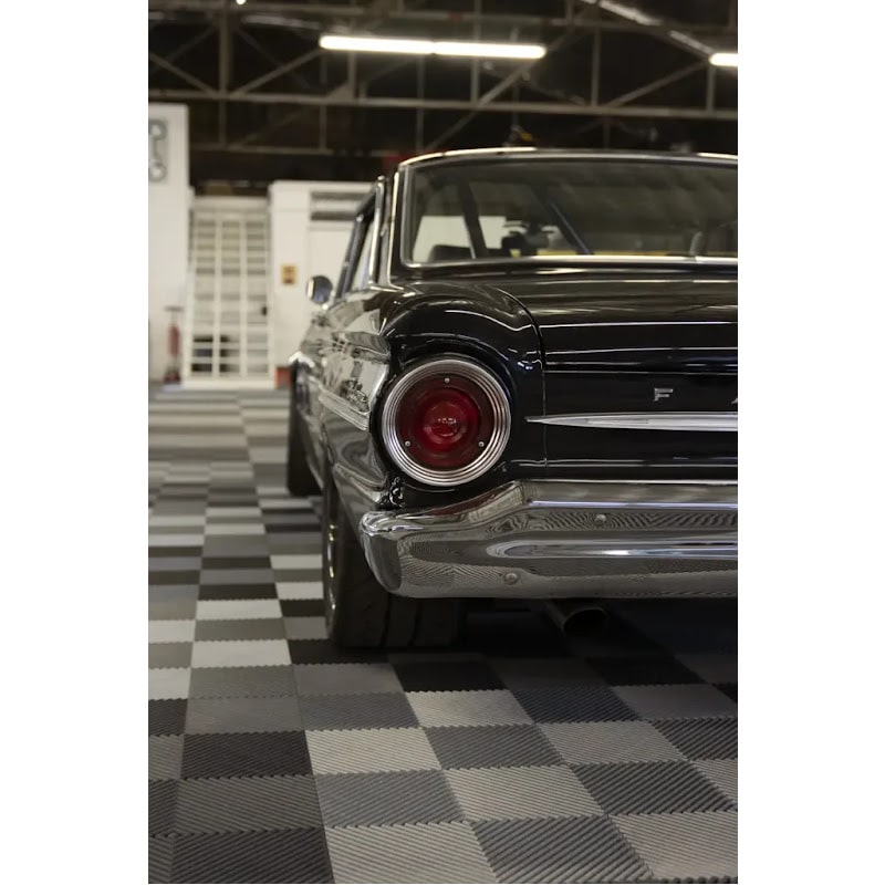 Classic car interior with RaceDeck Tiles XLC, highlighting a black vintage car on a stylish gray and black checkered floor