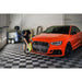 Detailing scene with XLC Race Track Flooring, showing a worker cleaning an orange Audi RS3 on a sleek checkered floor